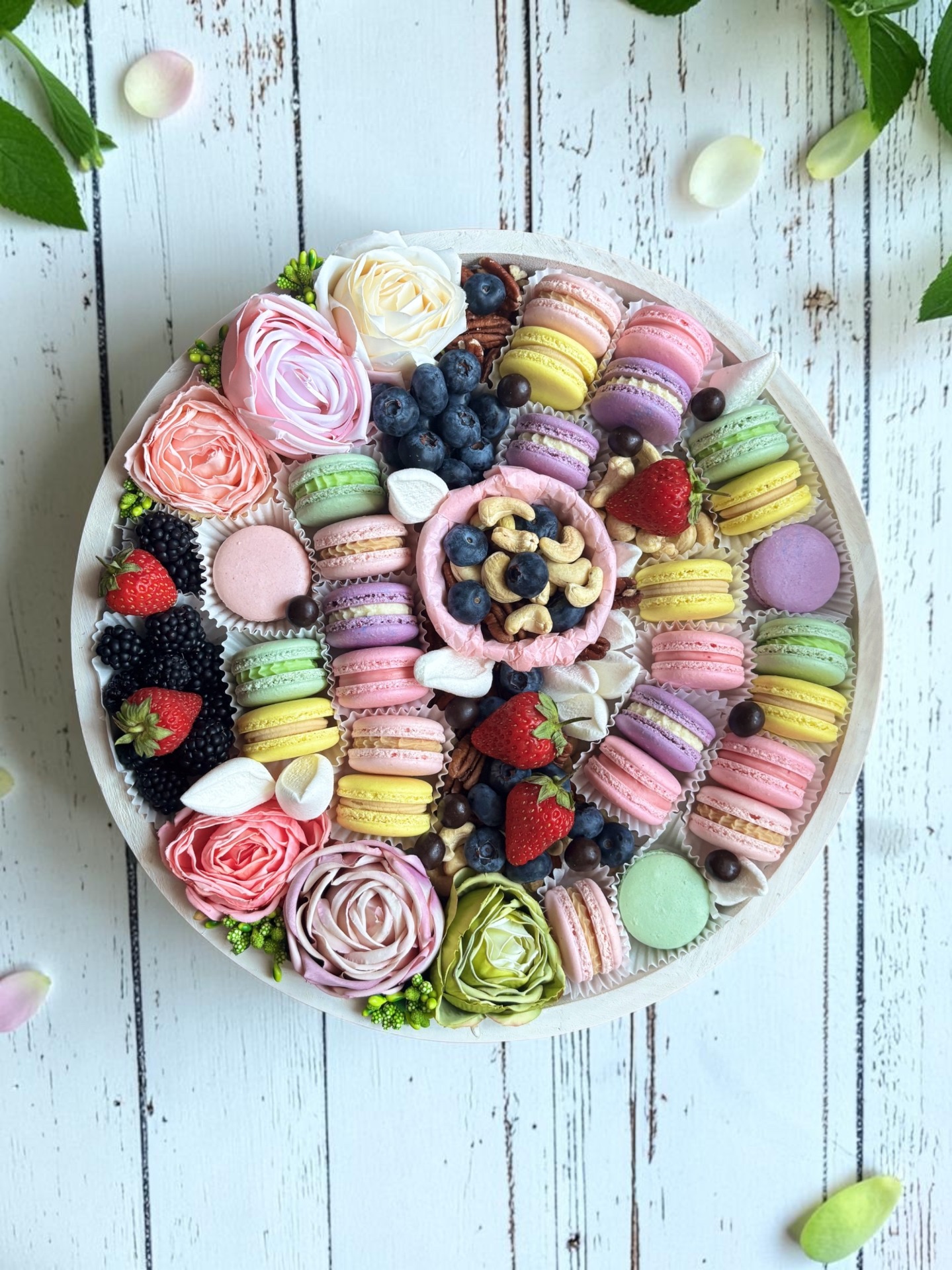 Kézműves macaron bőségtál friss gyümölcsökkel, magvakkal és virágdíszítéssel.